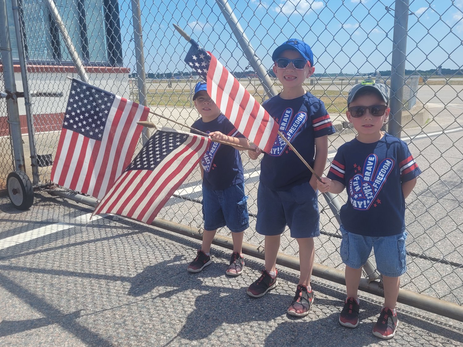 LITTLE PATRIOTS: Levi, 4, Cole, 6, and Rome, 4, stood with their father Trevor Wilson, waving American flags, hoping to catch a glimpse of President Biden